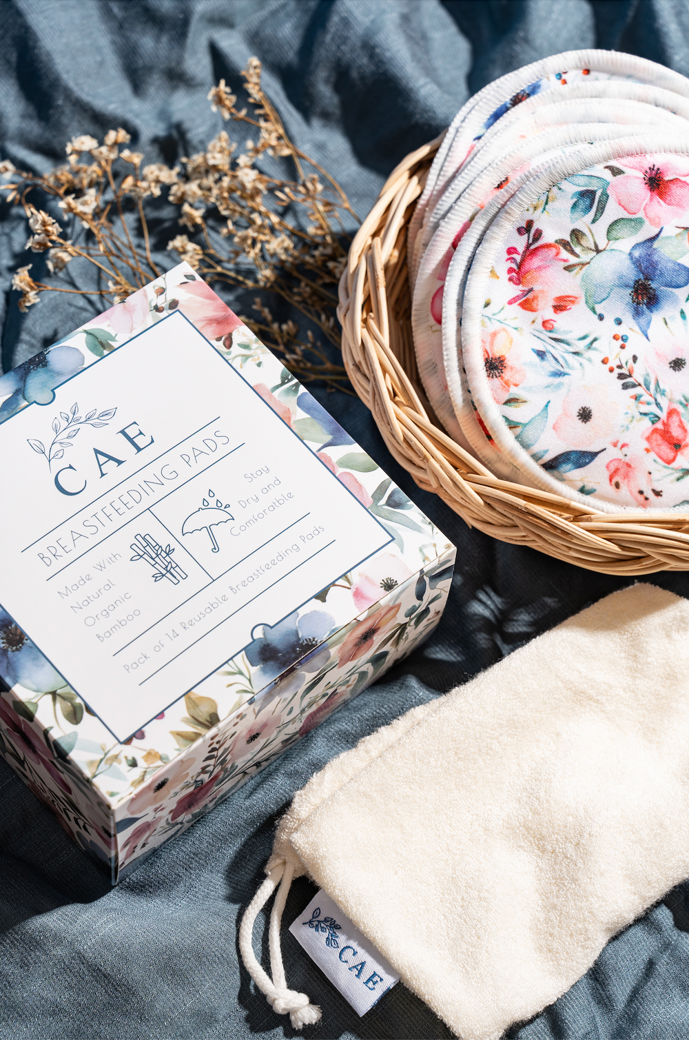 Reusable CAE bamboo nursing pad in a woven basket with lavender and linen