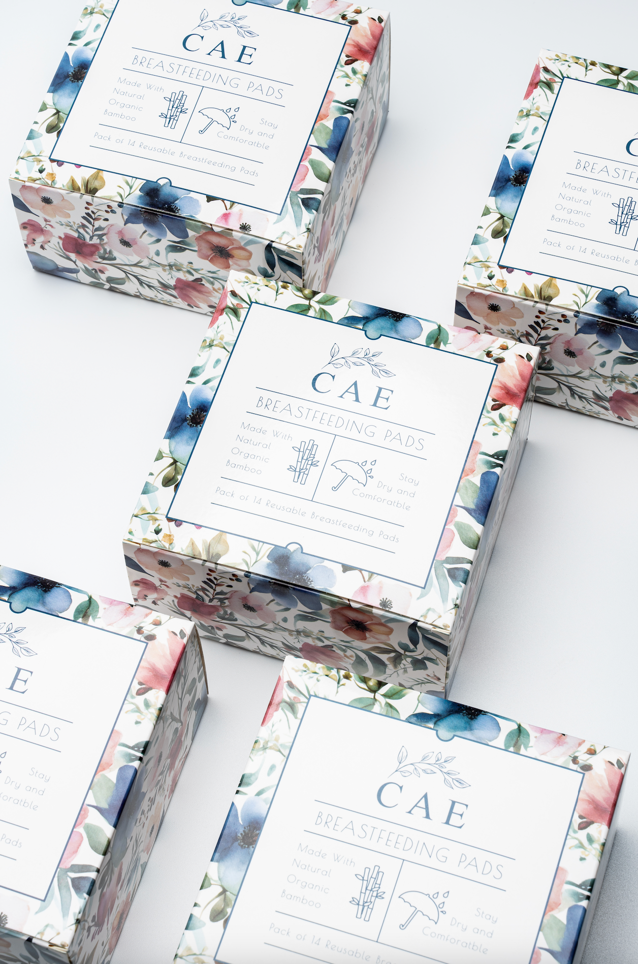 Several boxes of CAE reusable bamboo nursing pads with floral packaging